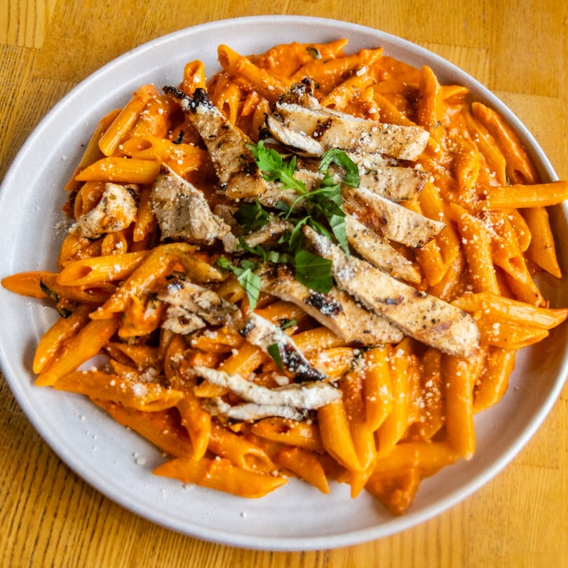 Penne pasta with grilled chicken, creamy red sauce, parmesan, and fresh herbs.